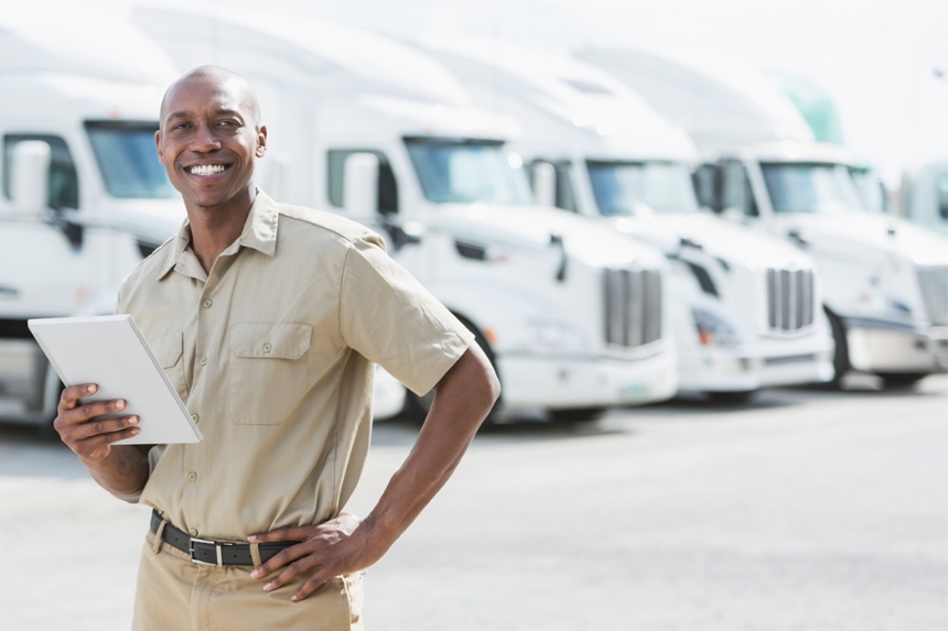 Employee holding tablet in front of line of trucks